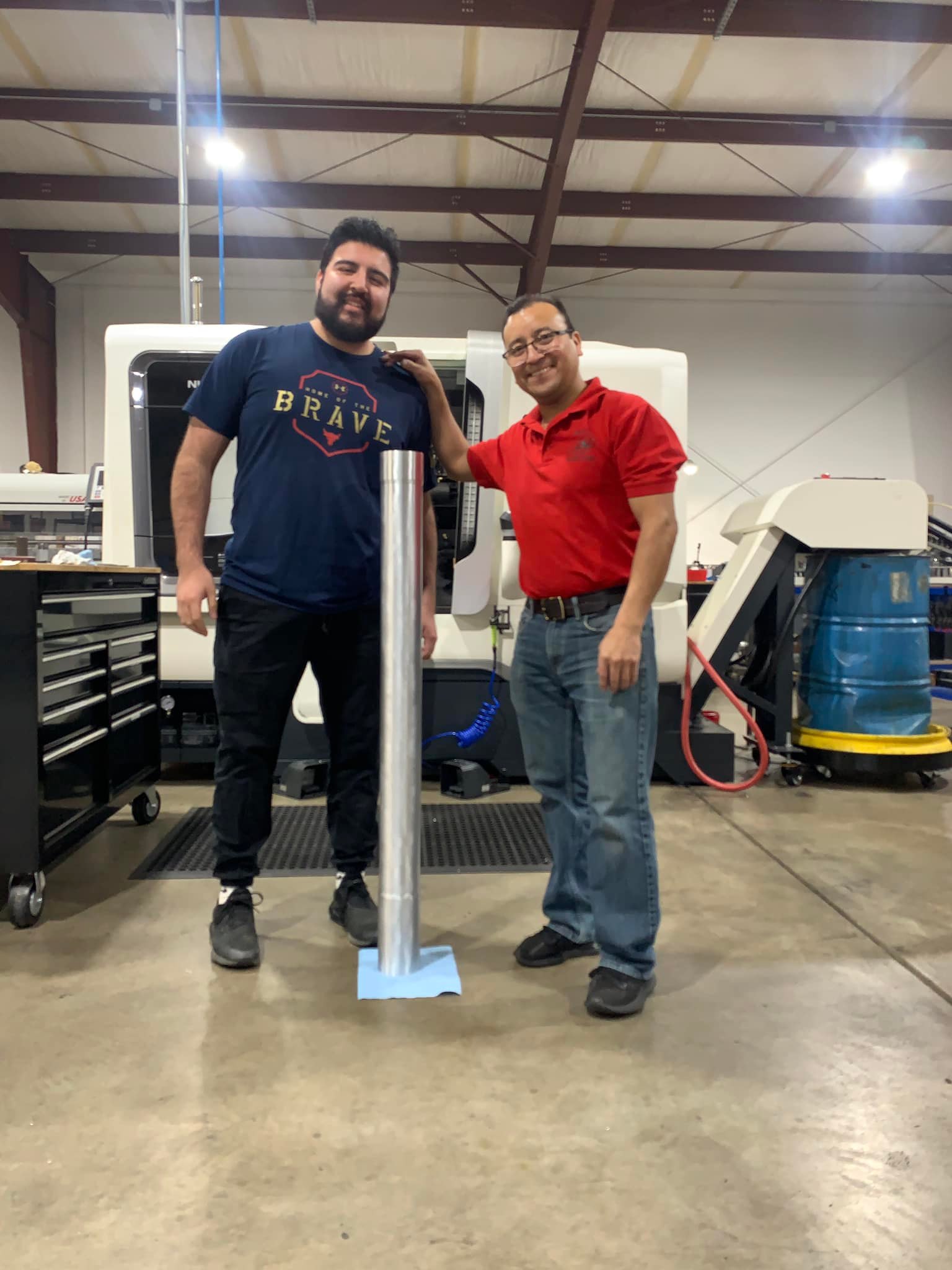 Two men standing next to a pole in a warehouse.