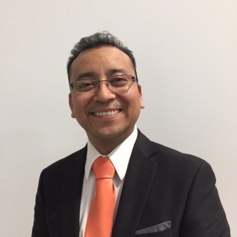 A man in a suit and tie smiling for the camera.