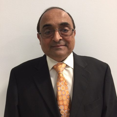 A man in a suit and tie standing up against a wall.